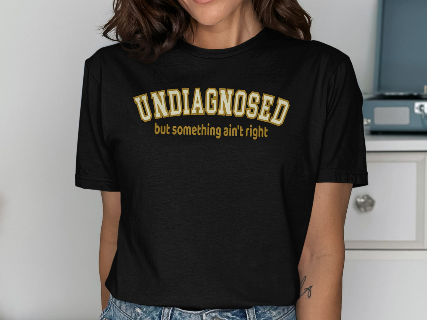 Black t-shirt with "UNDIAGNOSED" and "but something ain't right" text.