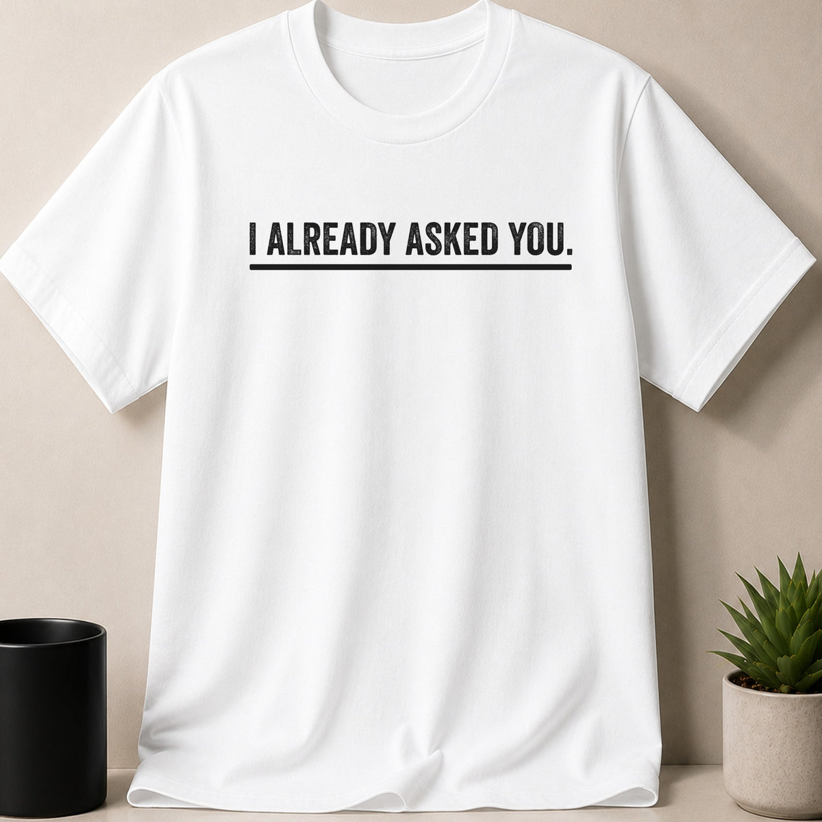 White t-shirt with black text that reads "I ALREADY ASKED YOU."