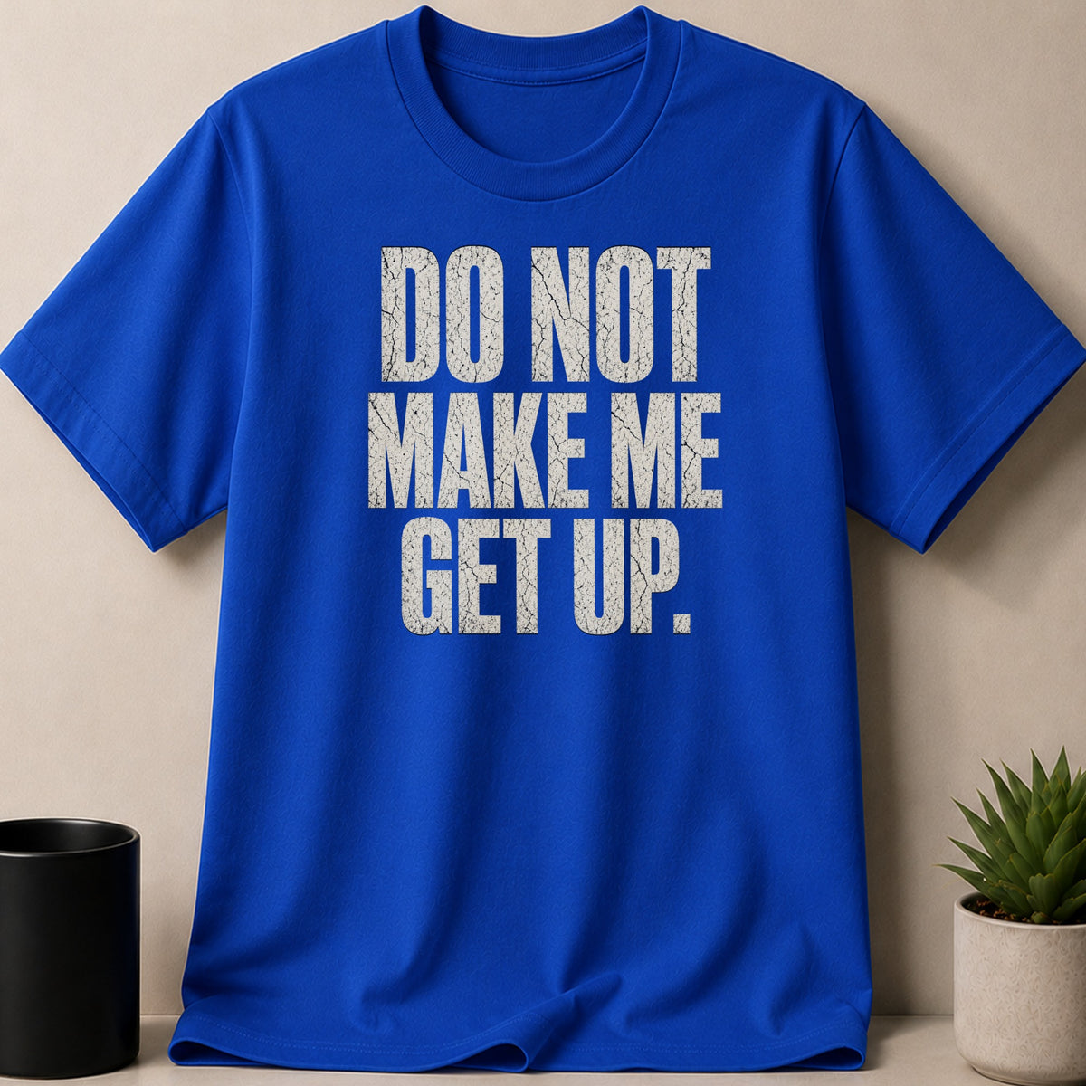 Blue t-shirt with white cracked text reading "DO NOT MAKE ME GET UP."