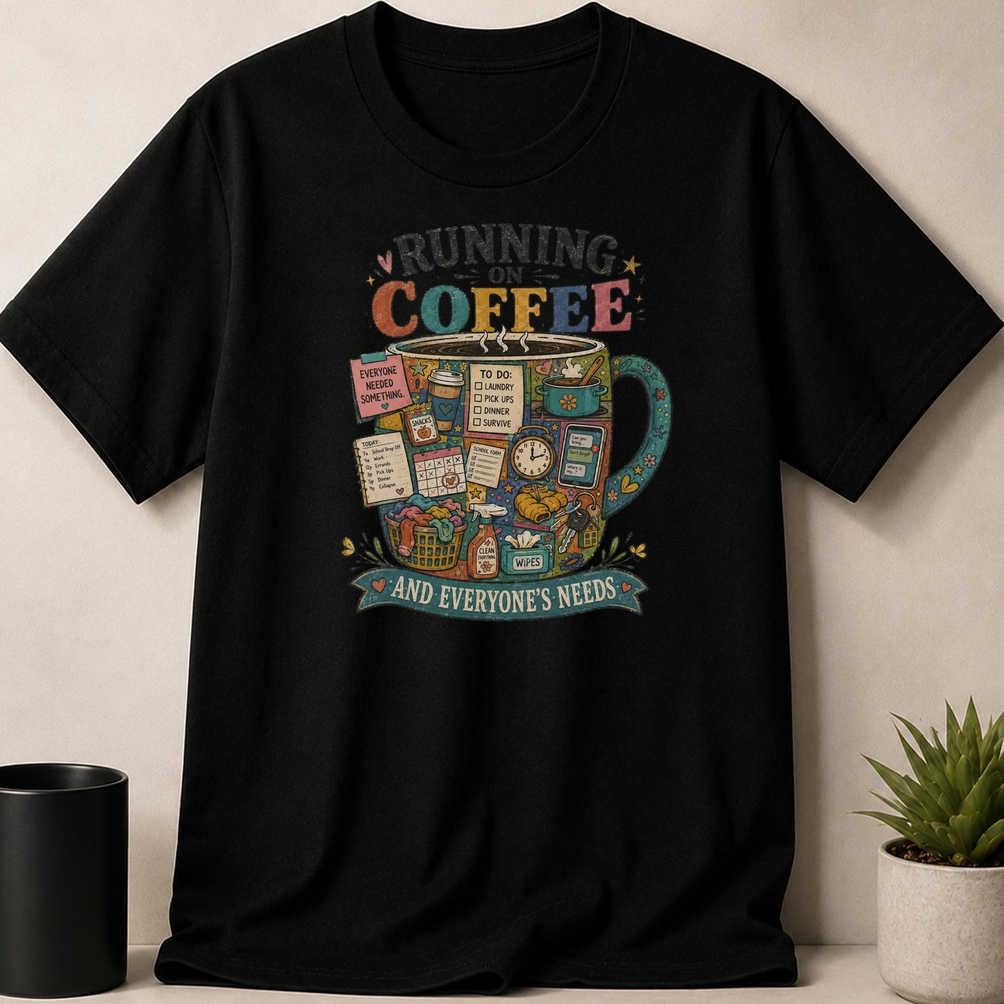 Black t-shirt with a colorful mug filled with items, reading "Running on Coffee and Everyone's Needs."