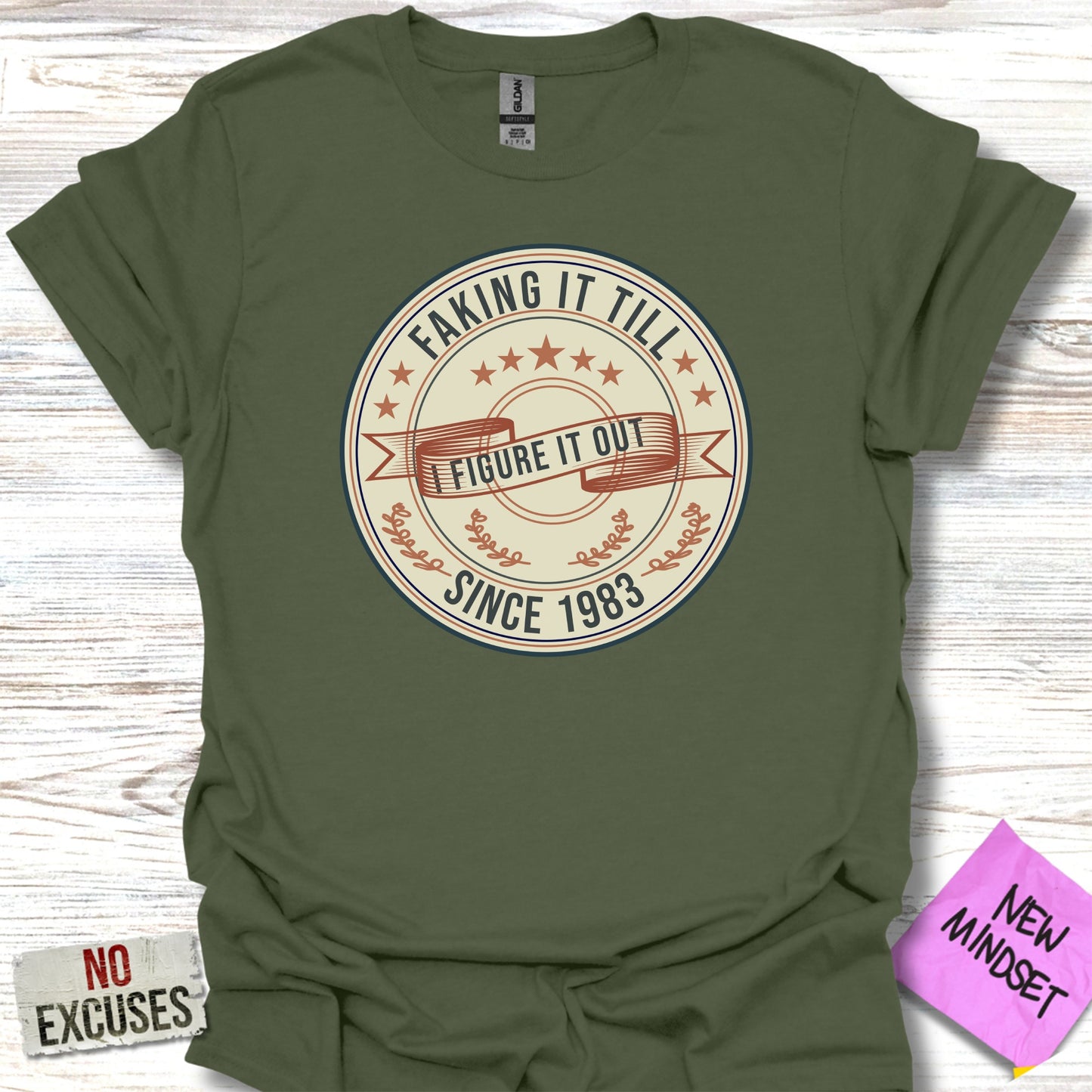 Green t-shirt with "Faking It Till I Figure It Out Since 1983" text.