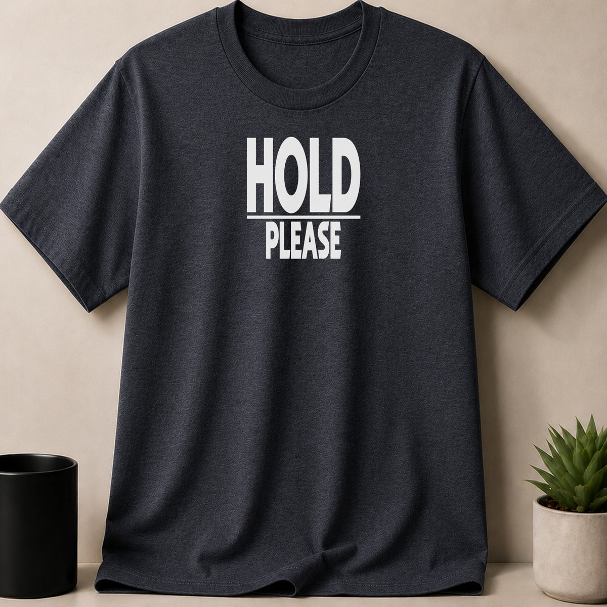 Dark grey t-shirt with white text "HOLD PLEASE" on the front.