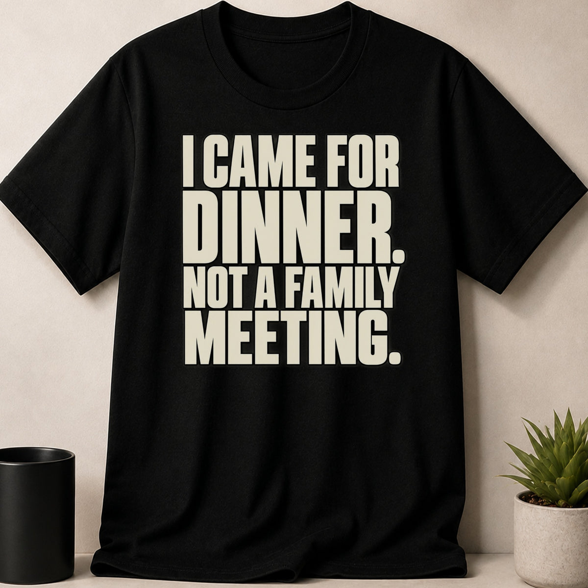 A black t-shirt printed with the beige text I CAME FOR DINNER. NOT A FAMILY MEETING.