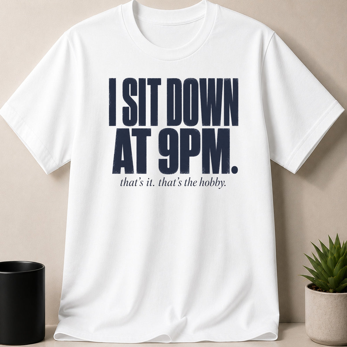 White t-shirt with navy text: "I SIT DOWN AT 9PM. that's it. that's the hobby."