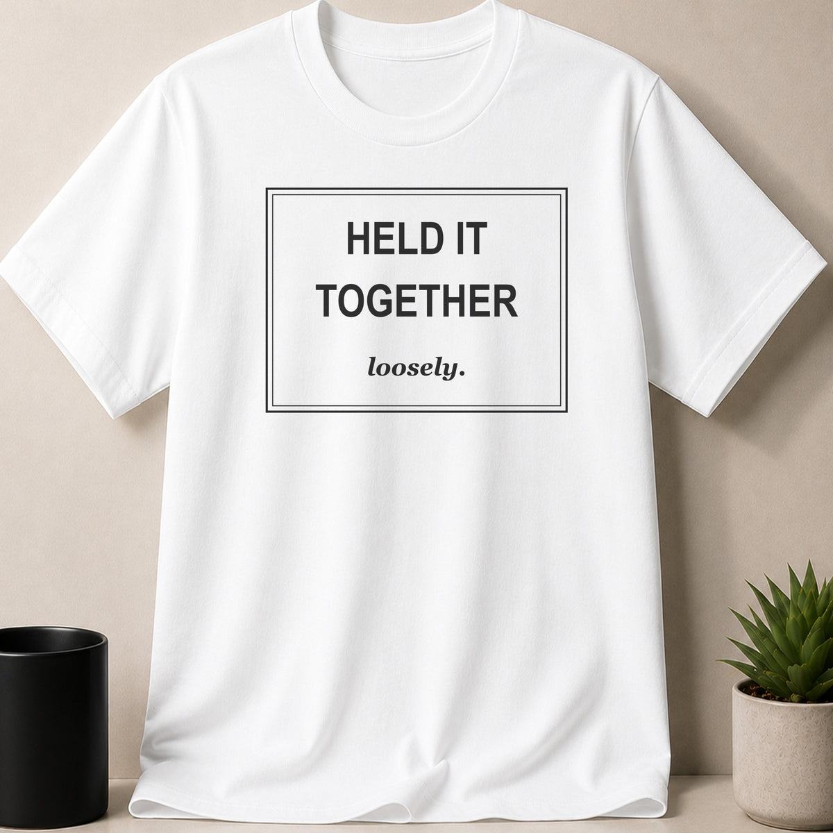 White t-shirt with "HELD IT TOGETHER loosely." text in a black box.
