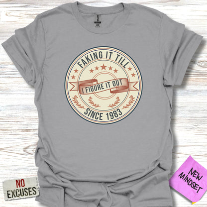 "Faking it till I figure it out" graphic with "Since 1983" on gray t-shirt.