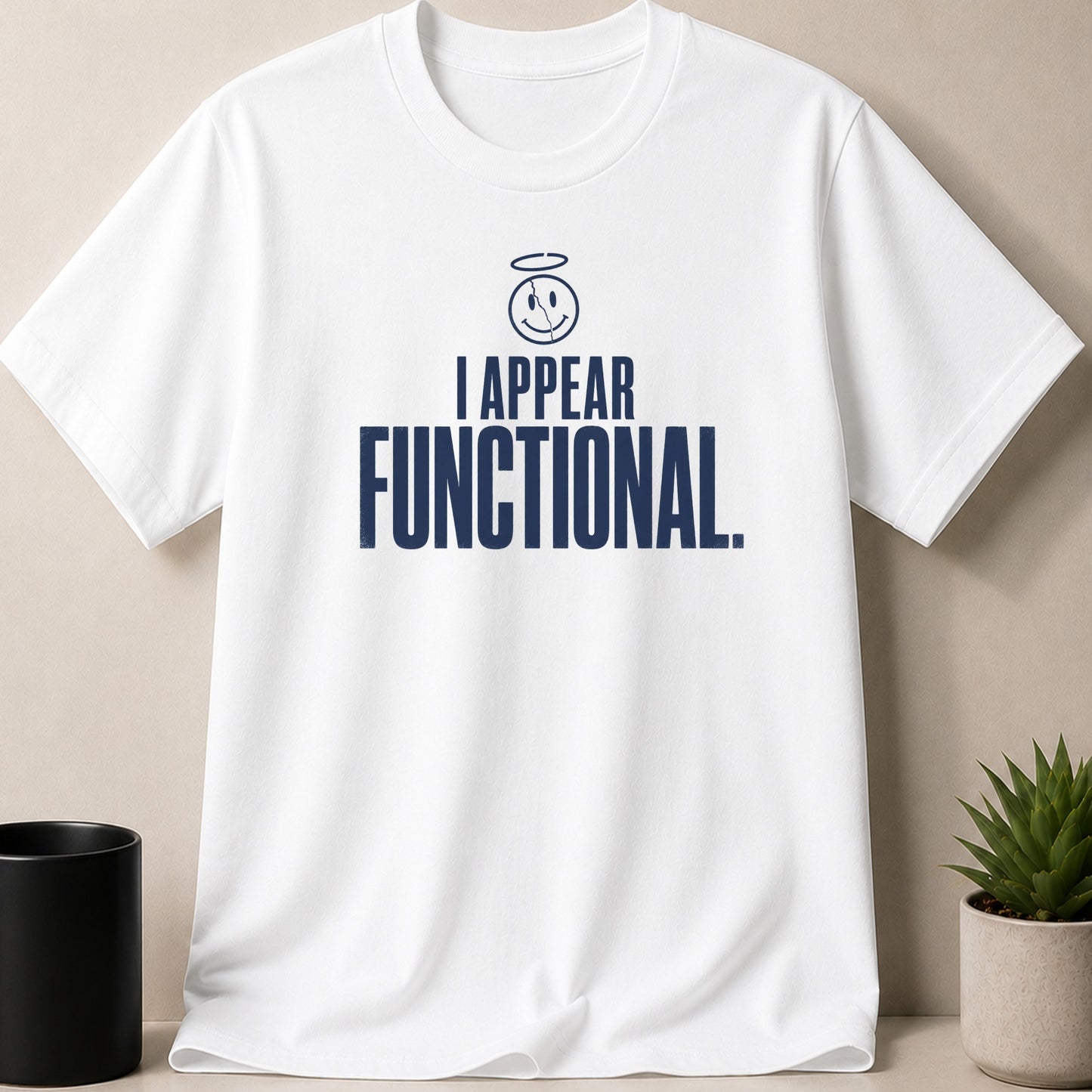 White t-shirt with navy text "I APPEAR FUNCTIONAL." and a cracked smiley face with halo.