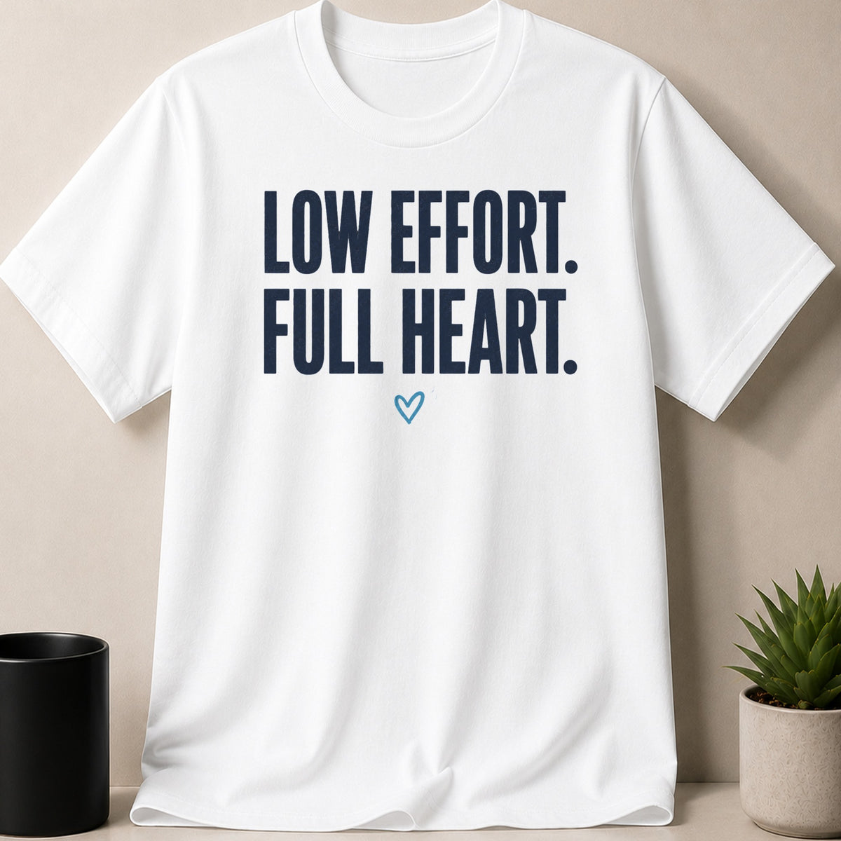 White t-shirt with navy text "LOW EFFORT. FULL HEART." and a small blue heart.