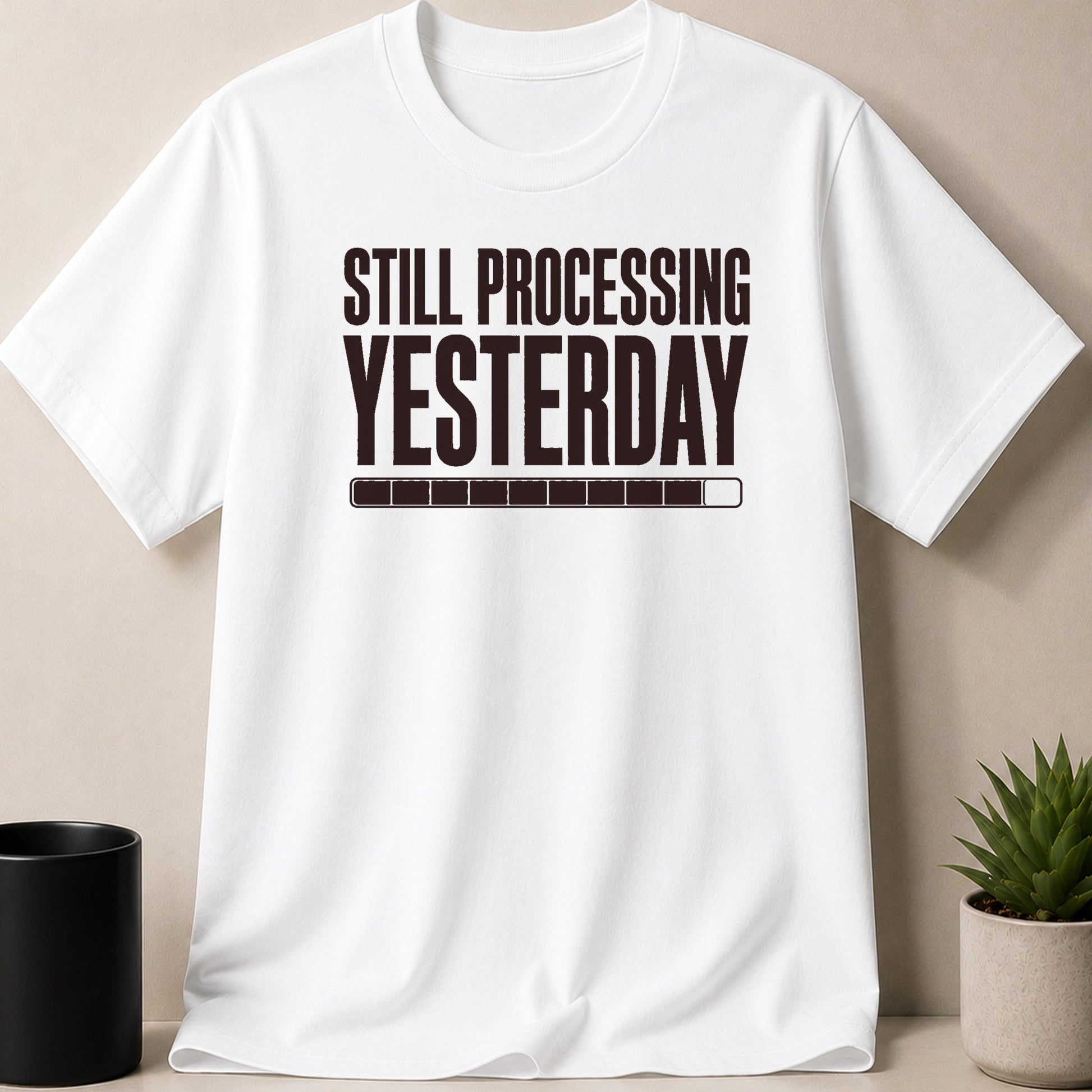 White t-shirt with dark text "STILL PROCESSING YESTERDAY" and a loading bar.