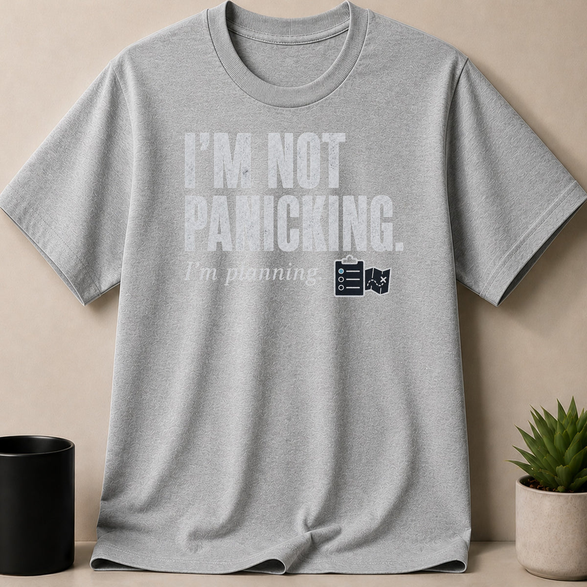Grey t-shirt with "I'm not panicking." and "I'm planning." text and icons.