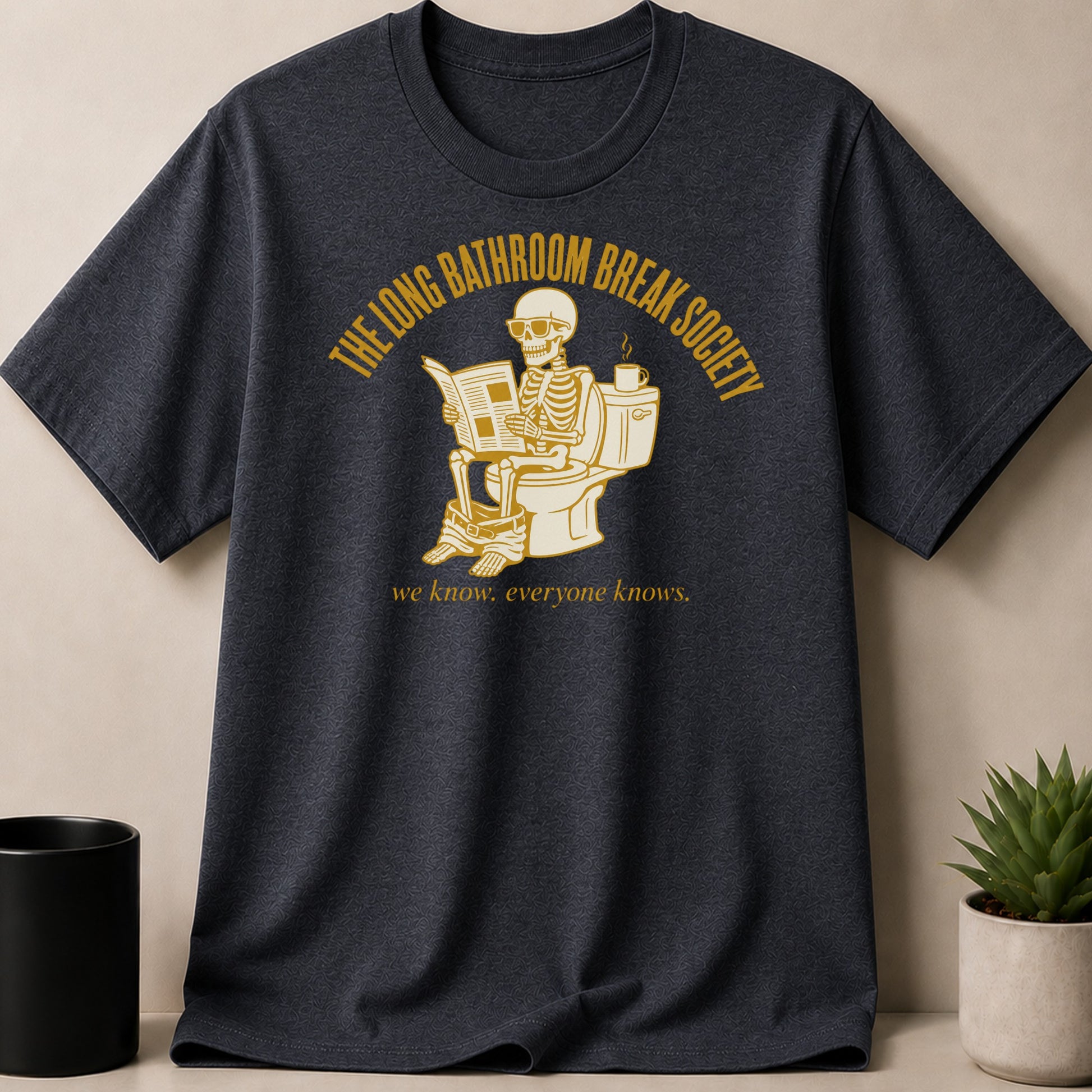 Dark t-shirt with skeleton on toilet reading newspaper. "The Long Bathroom Break Society" text.