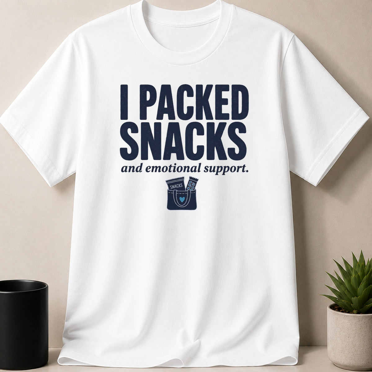 White t-shirt with navy text "I PACKED SNACKS and emotional support." and a snack bag graphic.