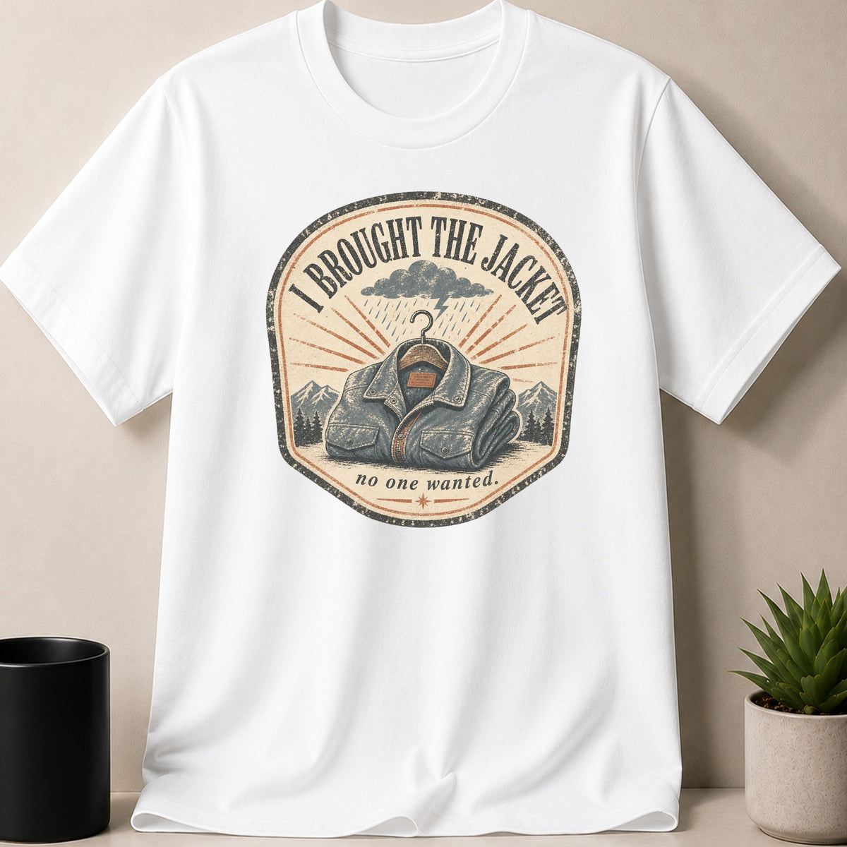 White t-shirt with a graphic that reads "I BROUGHT THE JACKET no one wanted."