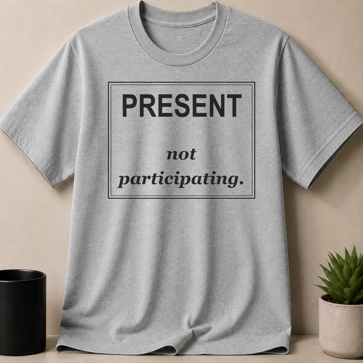 Gray t-shirt with black text inside a box: "PRESENT not participating."