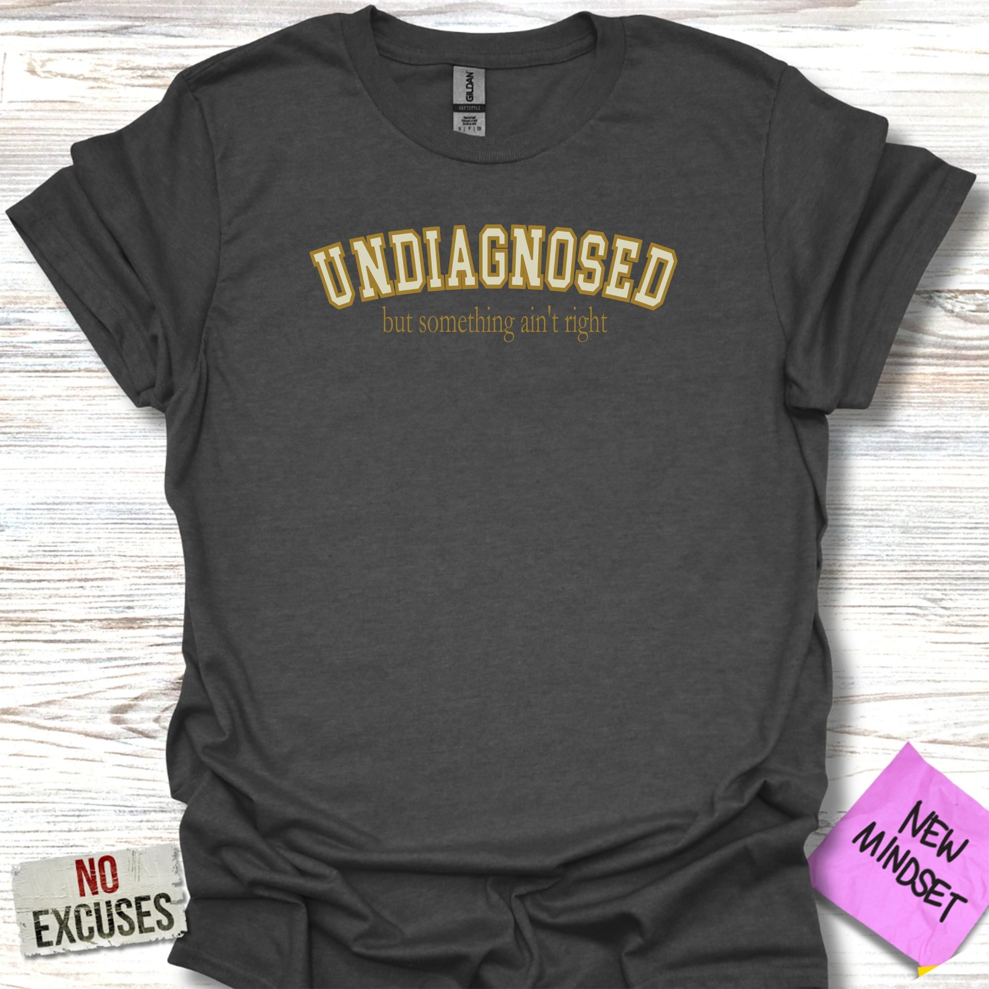 Dark t-shirt with "UNDIAGNOSED but something ain't right" in yellow text.