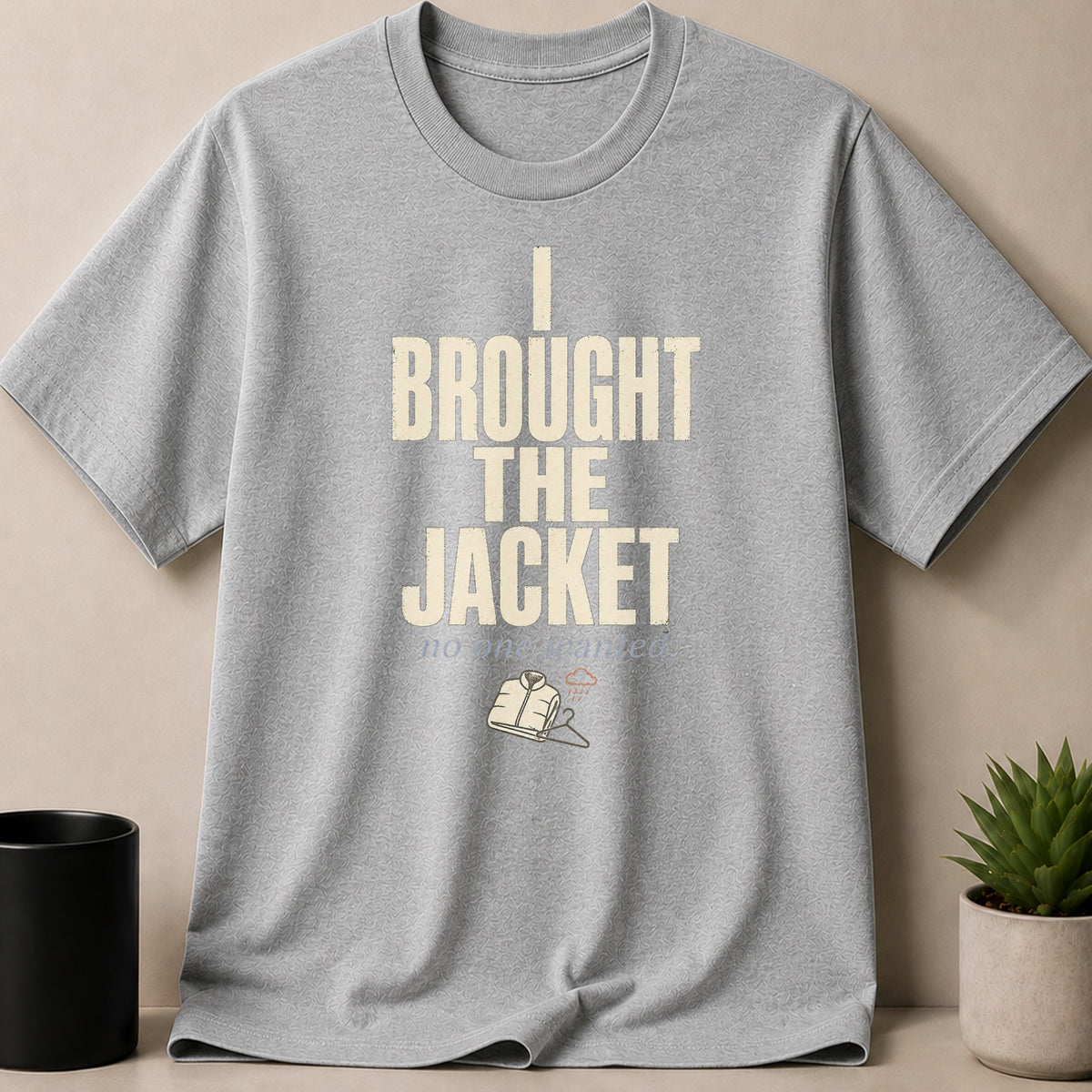 Grey t-shirt with text "I BROUGHT THE JACKET" and an illustration of a jacket.