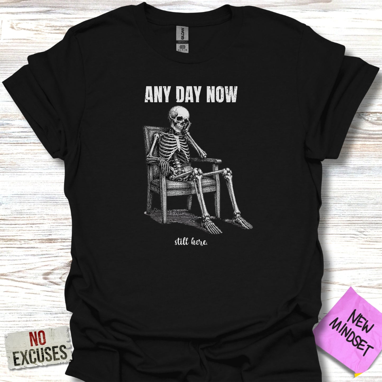 Black t-shirt with skeleton sitting in chair and "ANY DAY NOW" and "still here" text.