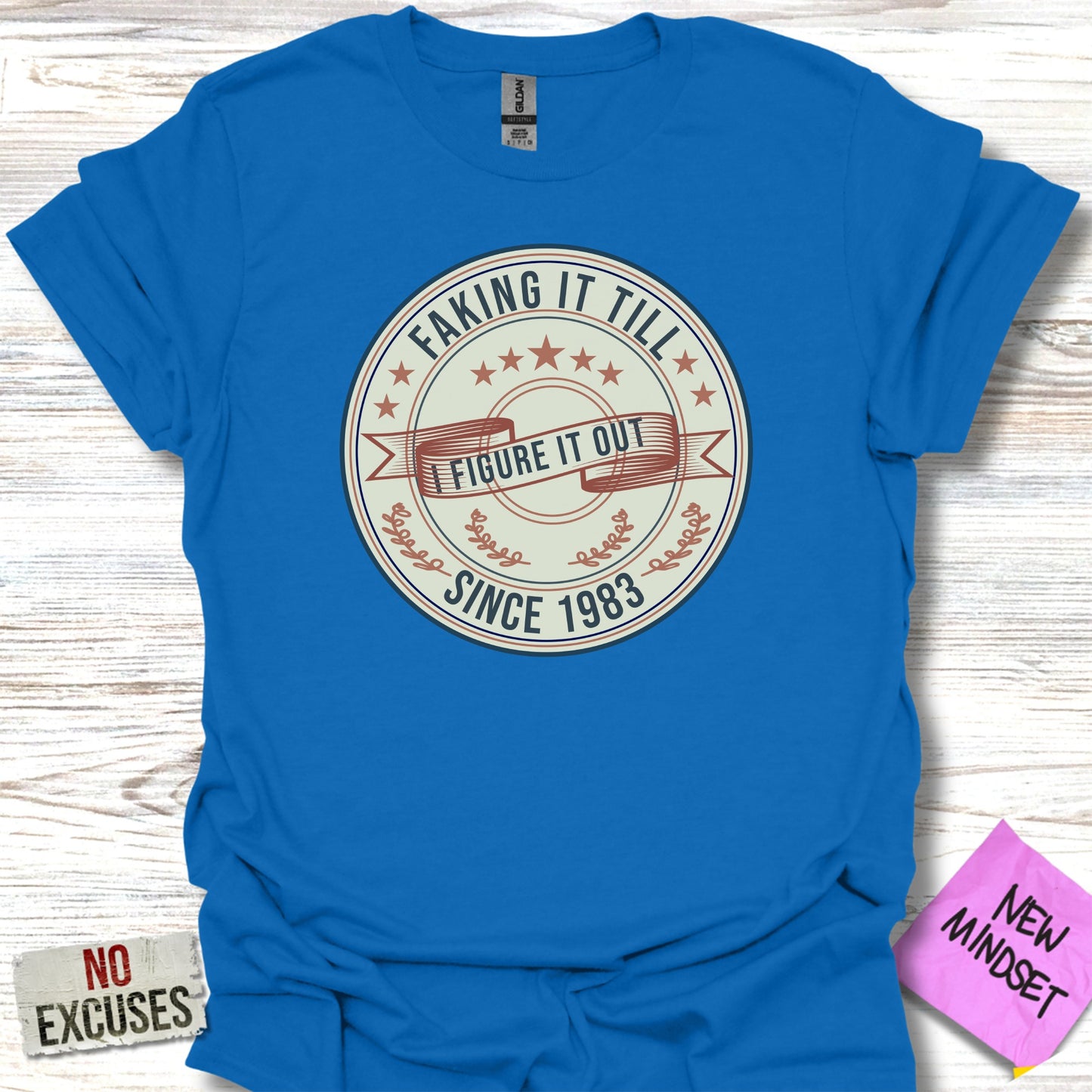 Blue t-shirt with "FAKING IT TILL I FIGURE IT OUT SINCE 1983" text.