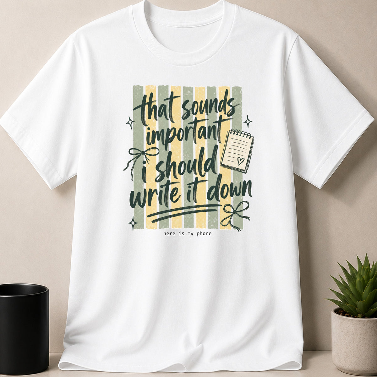White t-shirt with "that sounds important i should write it down" text and phone.