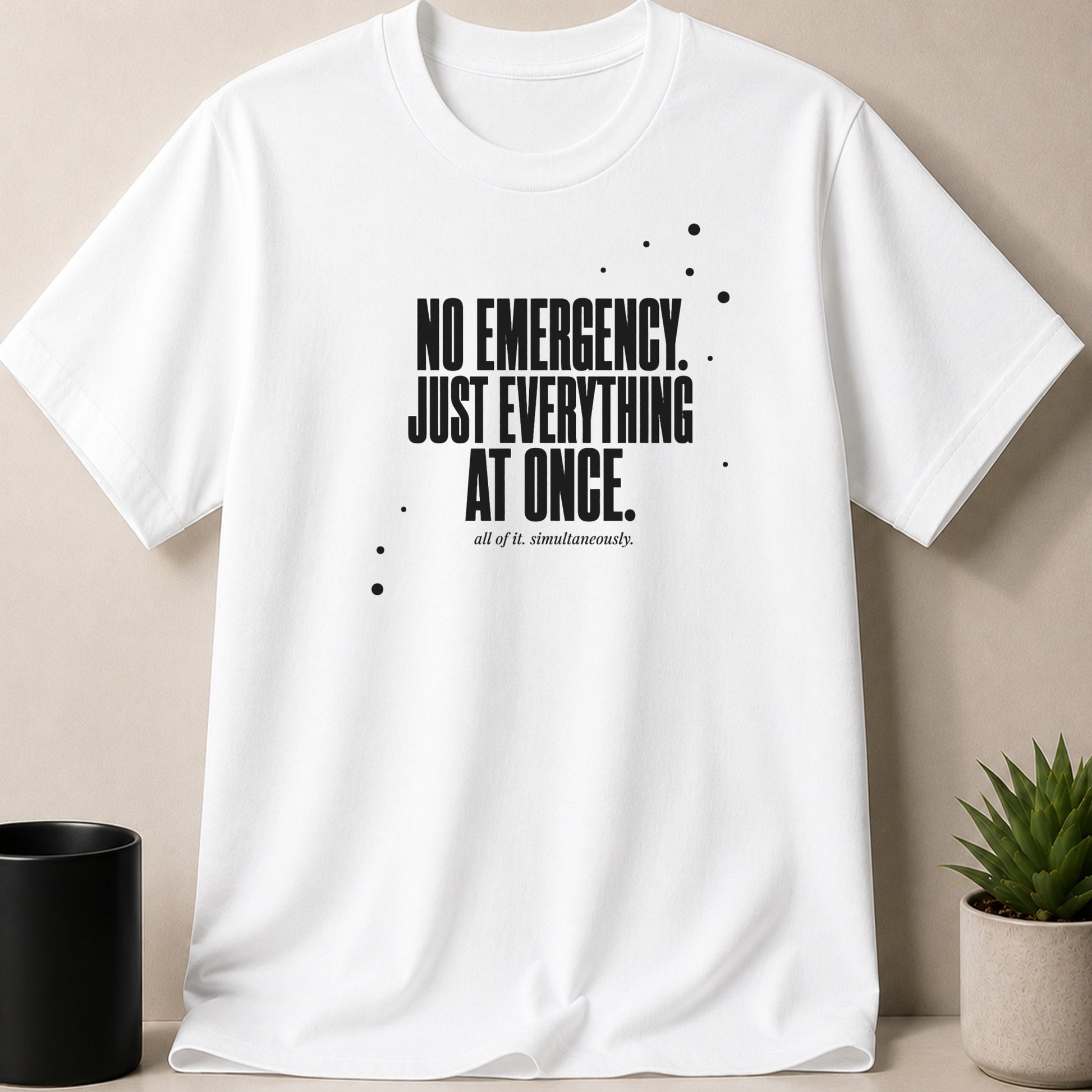 White t-shirt with black text "NO EMERGENCY. JUST EVERYTHING AT ONCE."