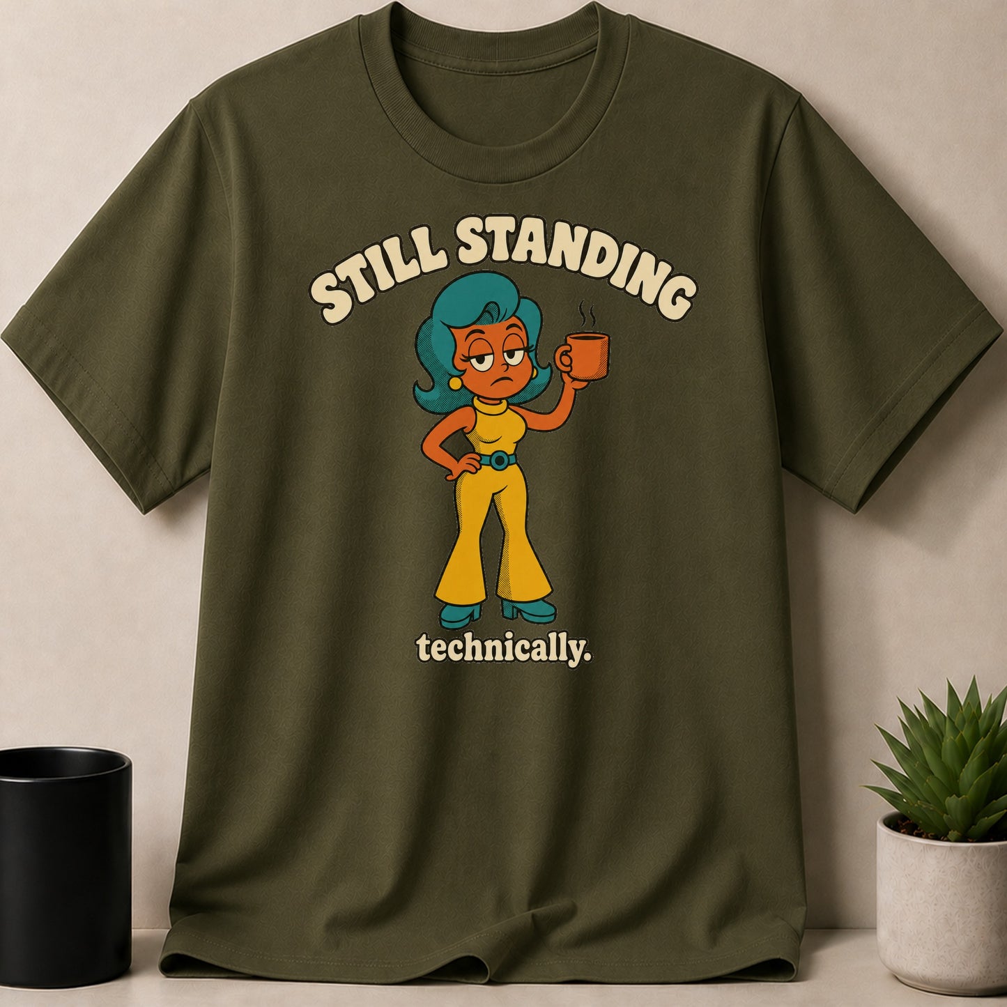 Olive green t-shirt with cartoon woman holding coffee and text "STILL STANDING technically."
