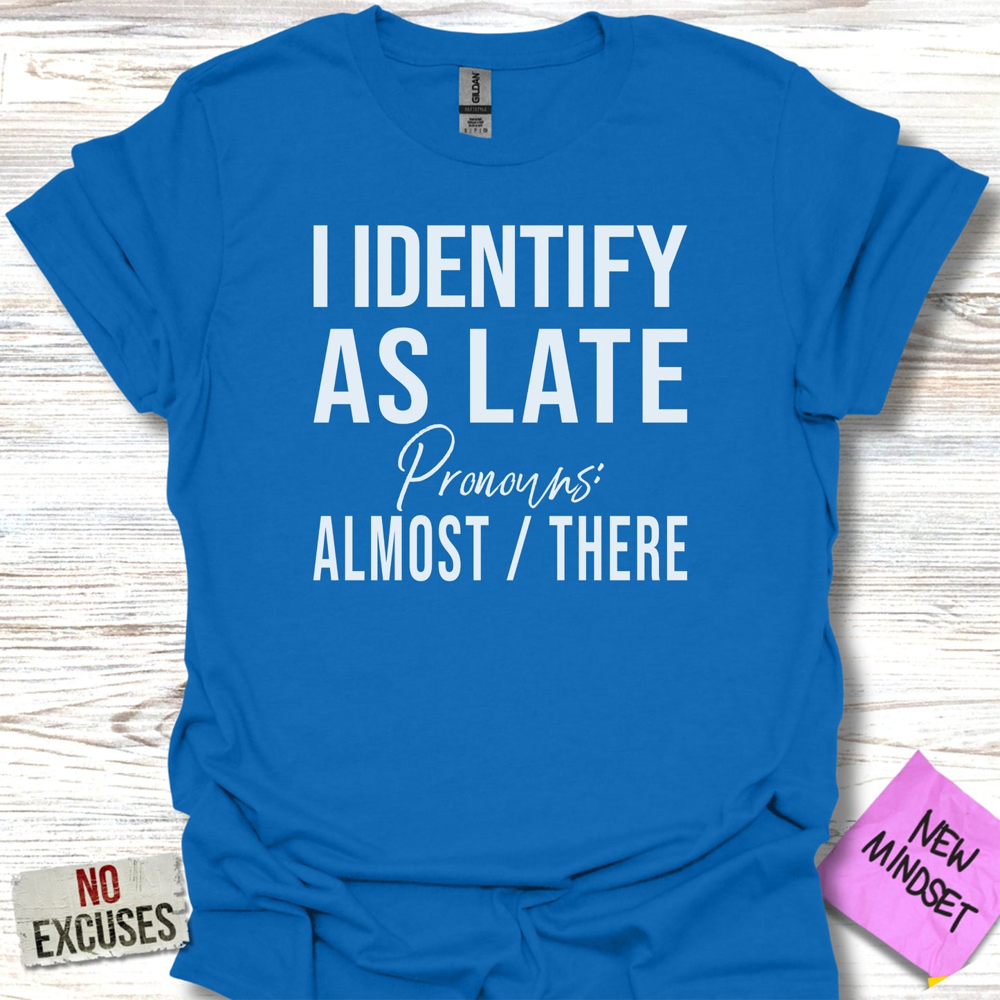 Blue t-shirt with "I identify as late, pronouns: almost / there" and "new mindset" text.