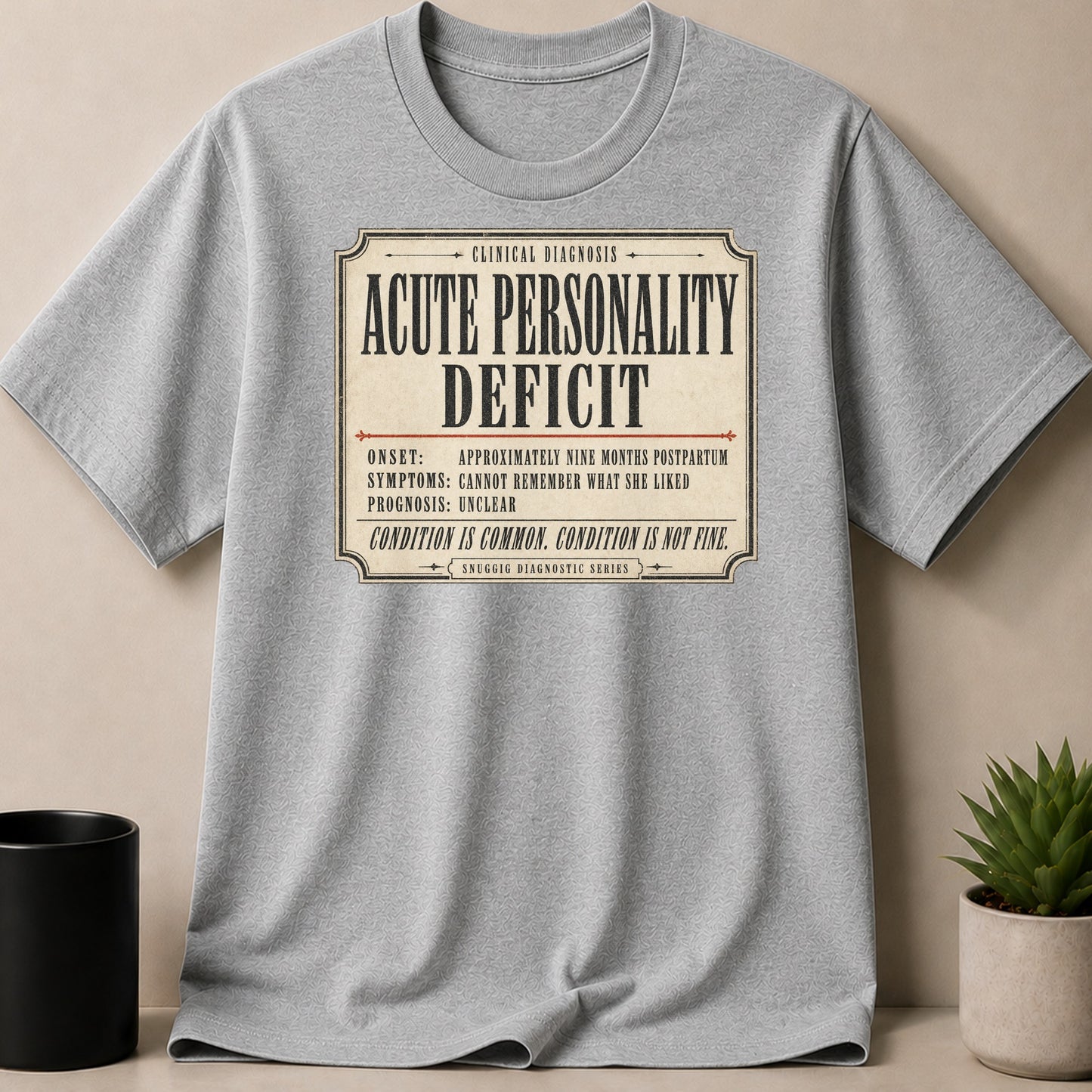 Grey t-shirt with graphic "ACUTE PERSONALITY DEFICIT" clinical diagnosis.