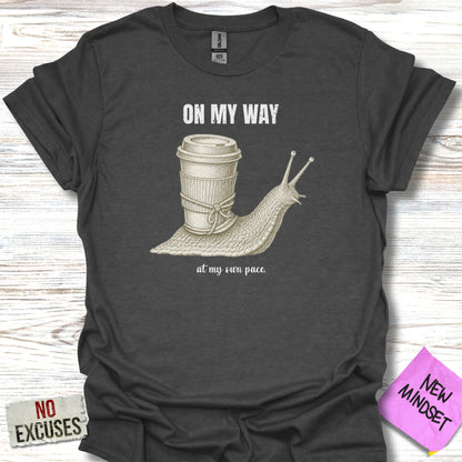 Dark gray t-shirt with a snail carrying a coffee cup, text reads "ON MY WAY at my own pace."