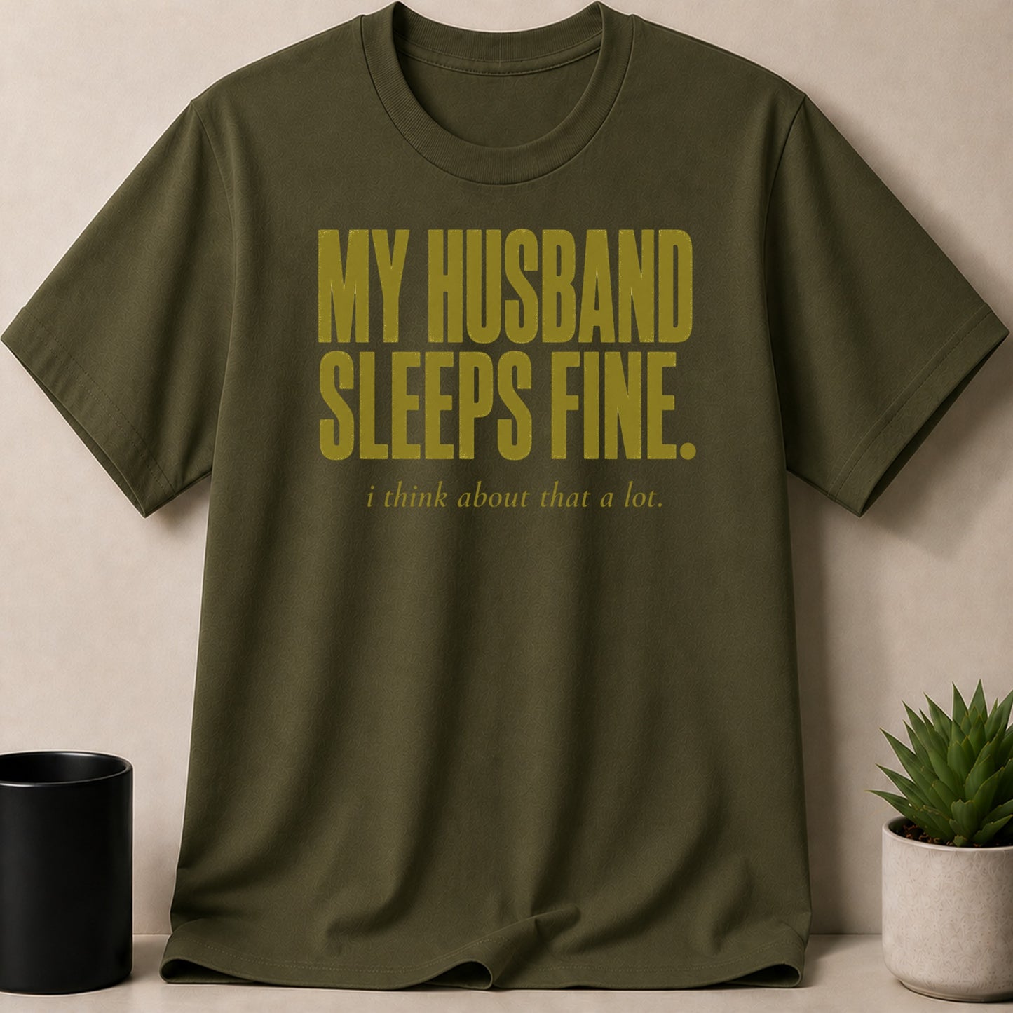 Olive green t-shirt with gold text "MY HUSBAND SLEEPS FINE. i think about that a lot."