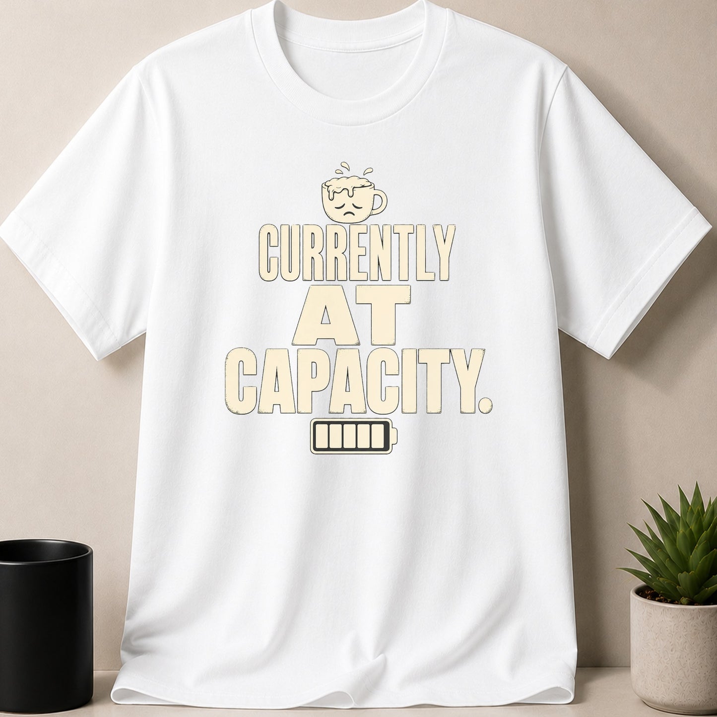 White t-shirt with text "CURRENTLY AT CAPACITY" and a sad coffee cup.
