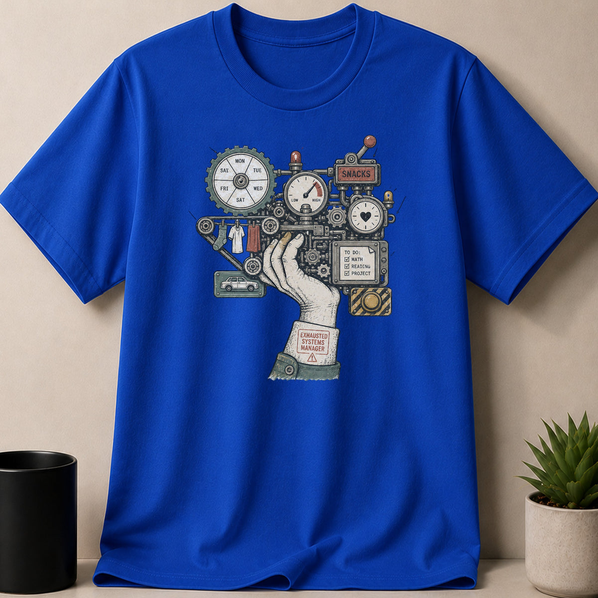 A blue t-shirt with a graphic of a complex machine with a hand and text "Exhausted Systems Manager".