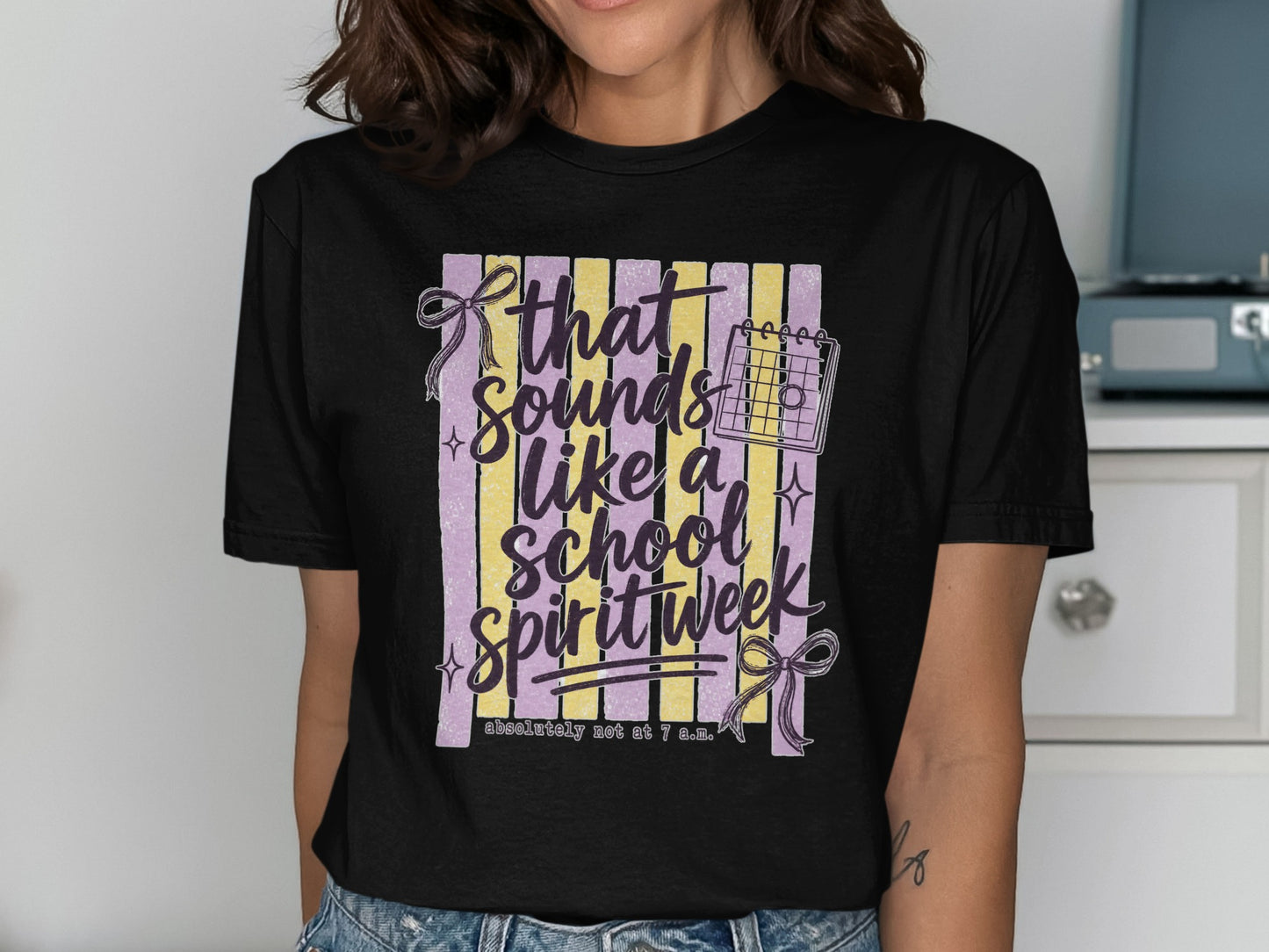 Black t-shirt graphic reads "that sounds like a school spirit week" with calendar icon and bows.
