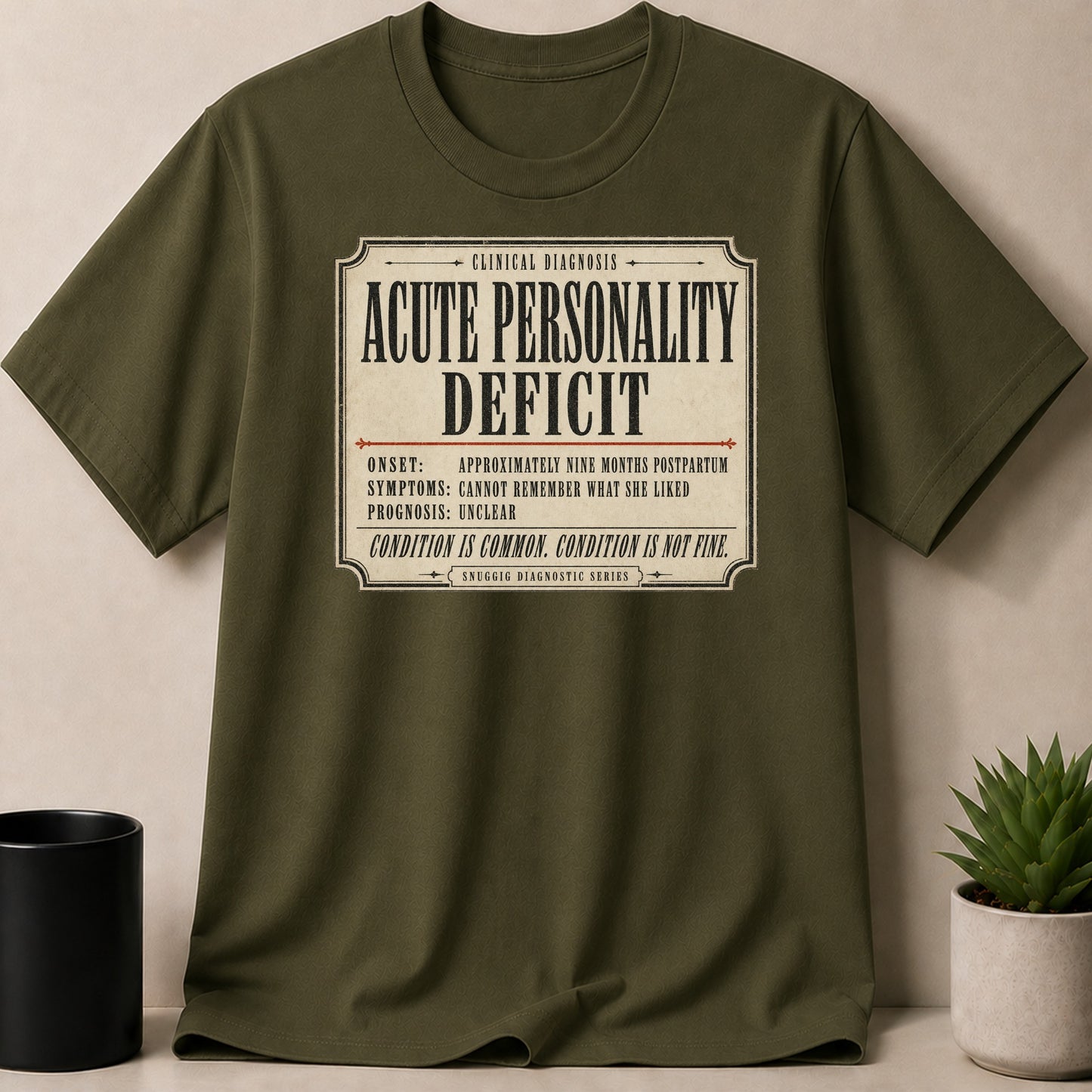 Olive green t-shirt with comedic "Acute Personality Deficit" clinical diagnosis print.
