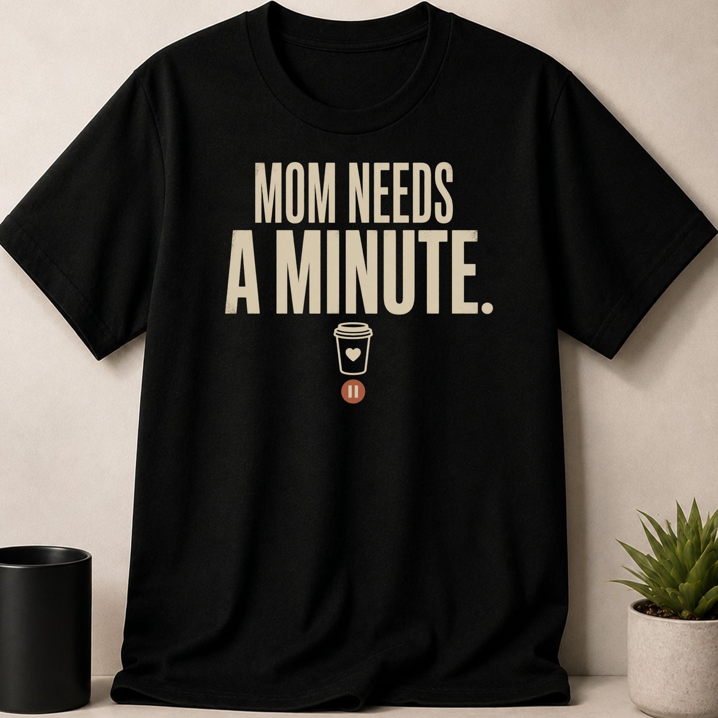 Black t-shirt with "MOM NEEDS A MINUTE." text and coffee cup icon.