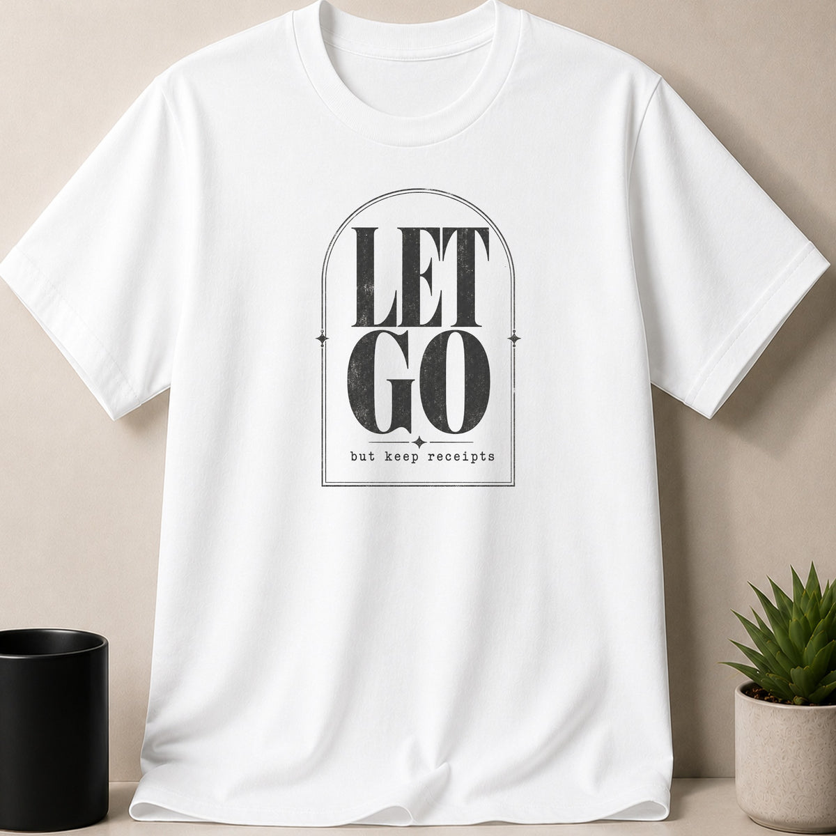 White t-shirt with text design "LET GO but keep receipts" inside an arched frame.