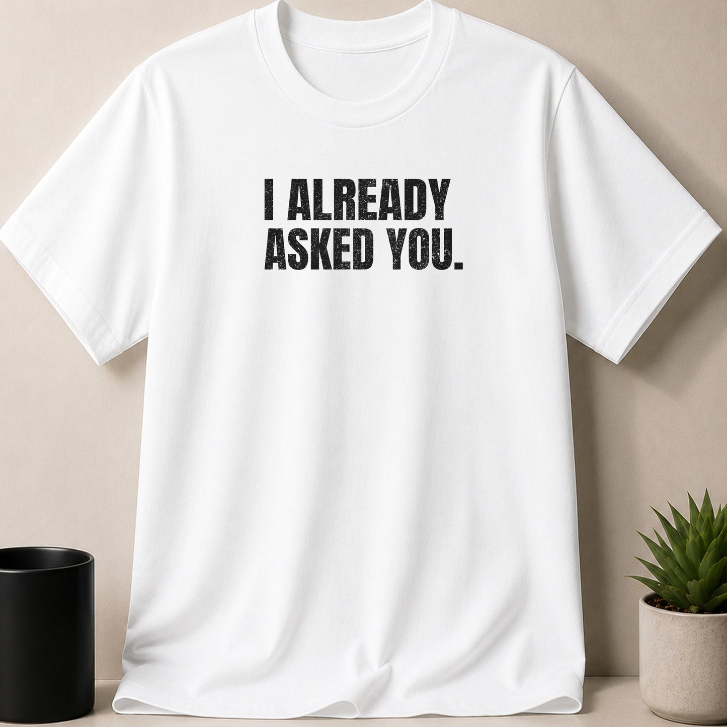 White t-shirt with black text that reads "I ALREADY ASKED YOU."