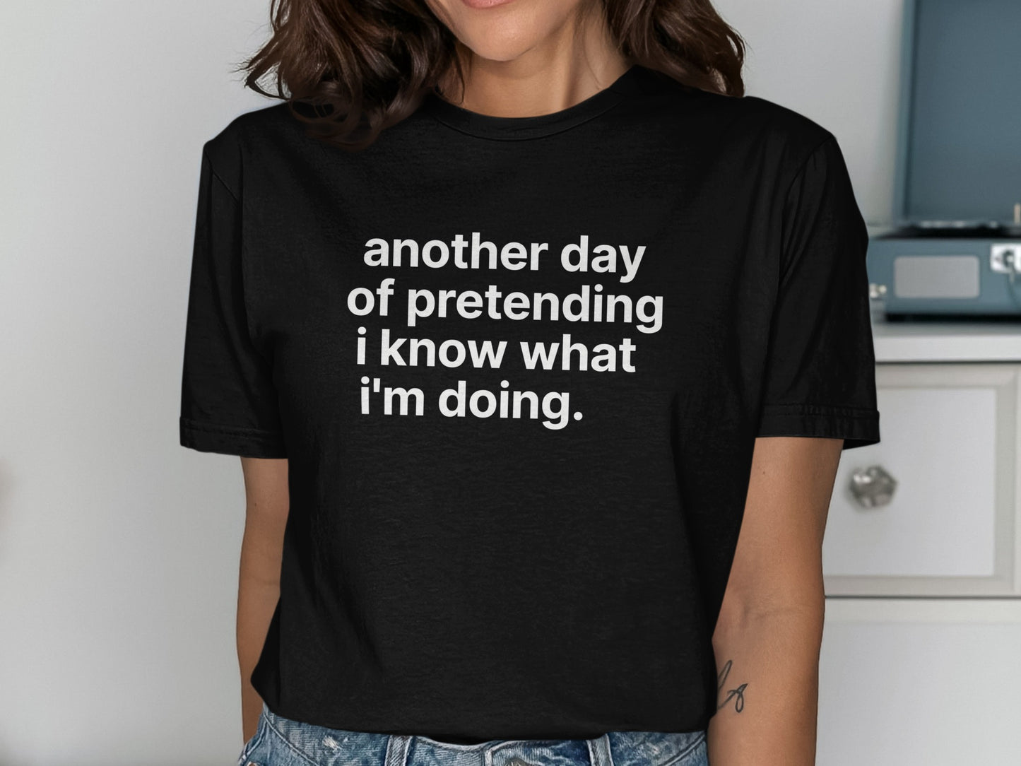 Black t-shirt with white text saying "another day of pretending i know what i'm doing."
