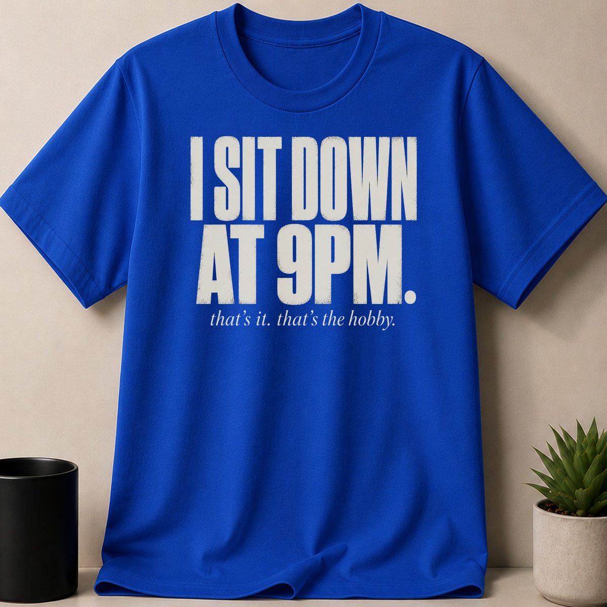 Blue t-shirt with white text: "I SIT DOWN AT 9PM. that's it. that's the hobby."