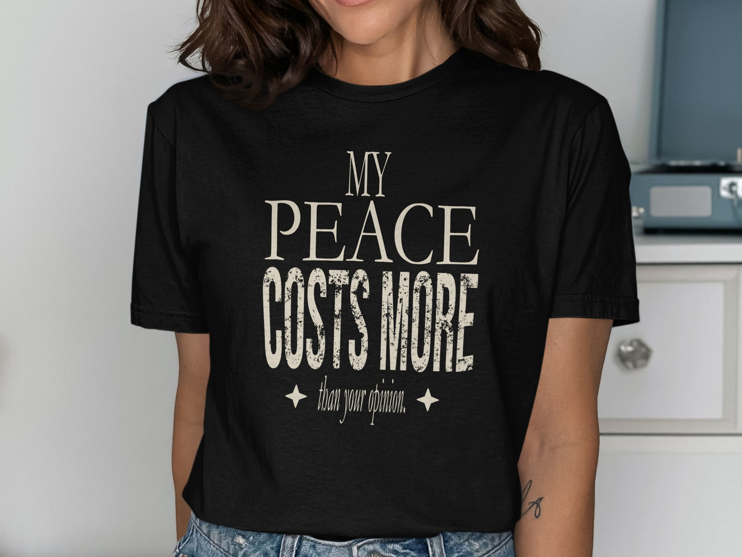 Black t-shirt with distressed text reading "My Peace Costs More Than Your Opinion."