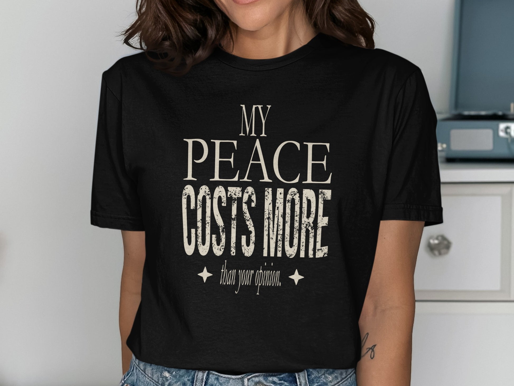 Black t-shirt with distressed text reading "My Peace Costs More Than Your Opinion."