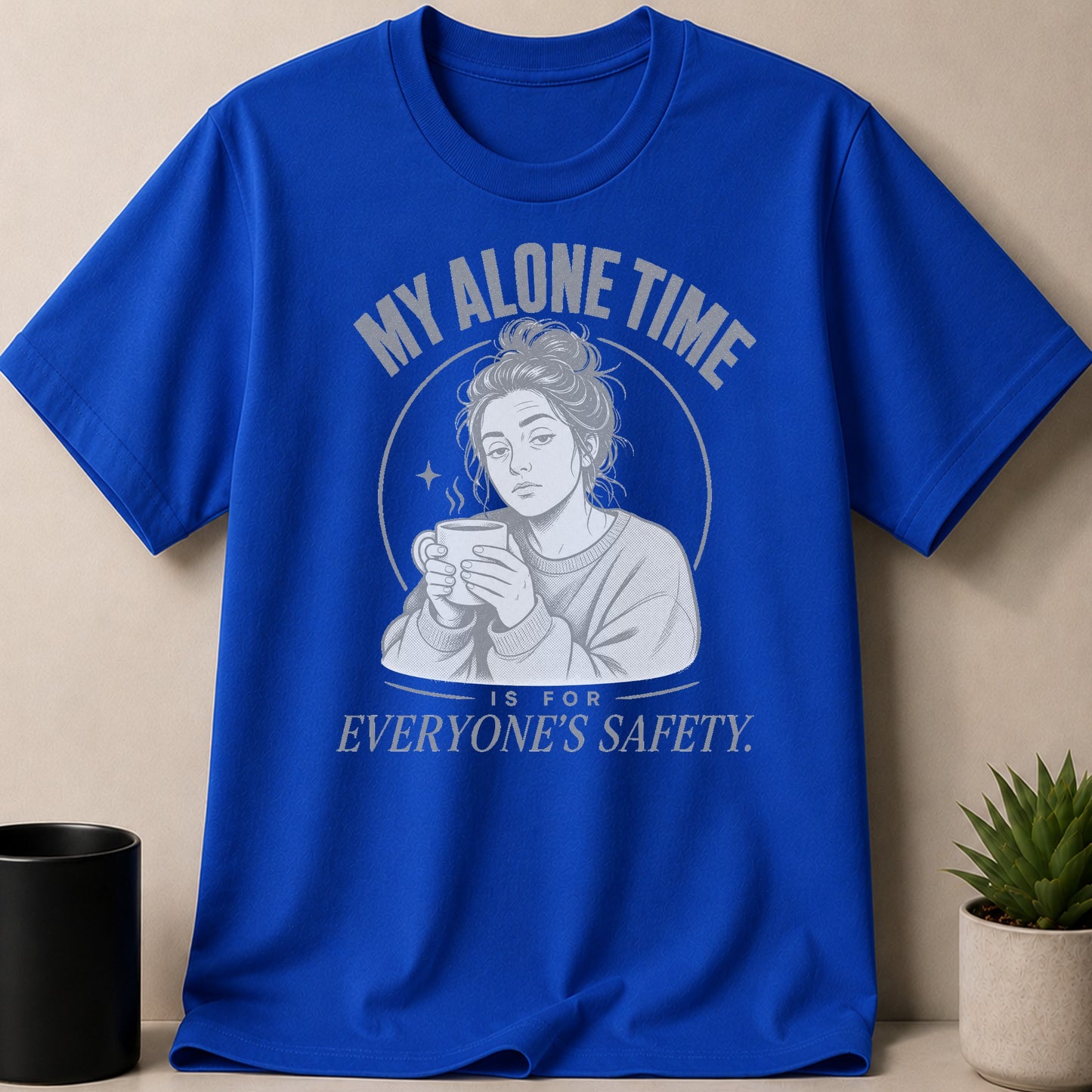 Blue t-shirt with illustration of woman holding coffee mug and text "MY ALONE TIME IS FOR EVERYONE'S SAFETY".