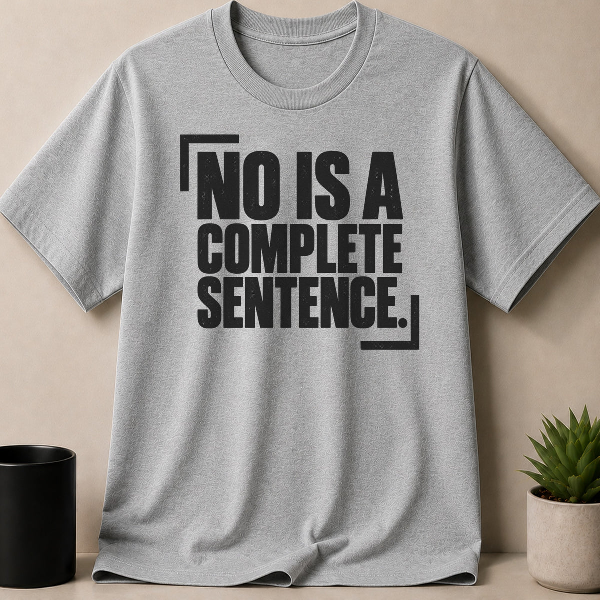 A grey t-shirt featuring the black text NO IS A COMPLETE SENTENCE inside corner brackets.