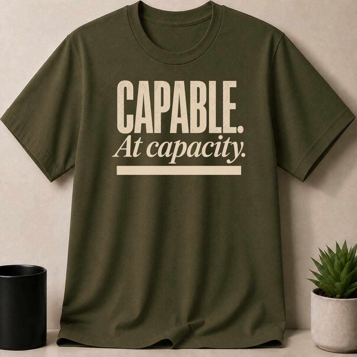 Olive green t-shirt with "CAPABLE. At capacity." text in cream.