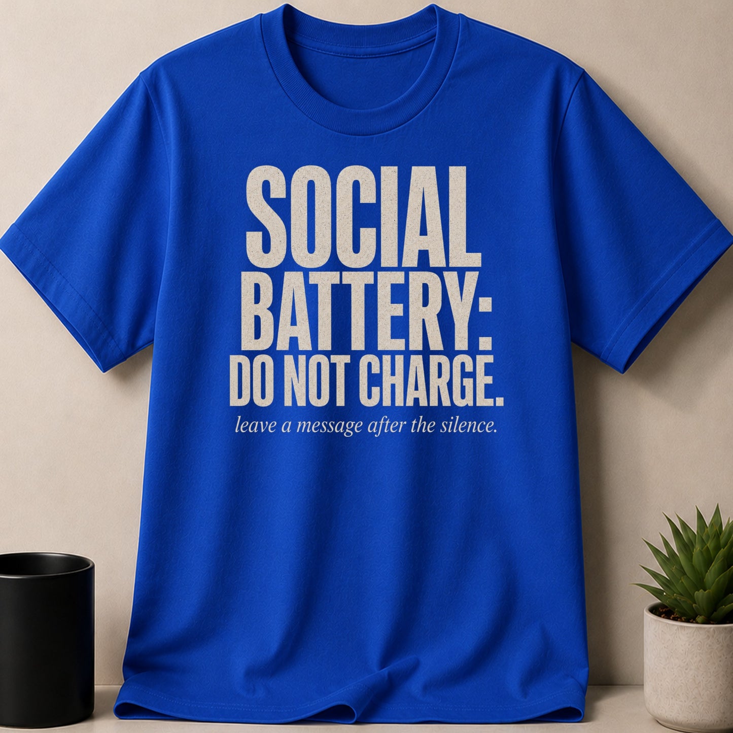 Blue t-shirt with text "SOCIAL BATTERY: DO NOT CHARGE. leave a message after the silence."