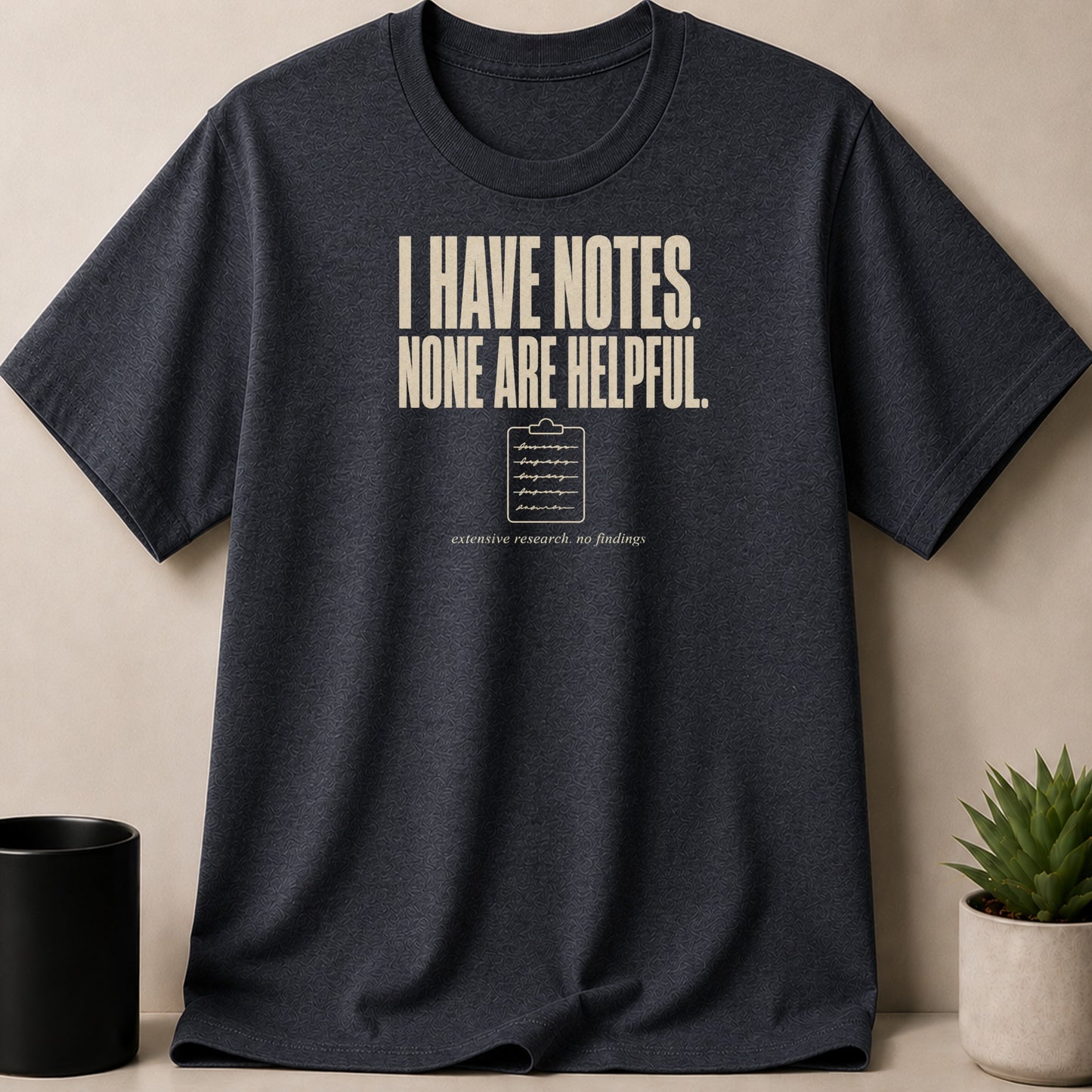 Dark grey t-shirt with text "I HAVE NOTES. NONE ARE HELPFUL." and a clipboard.