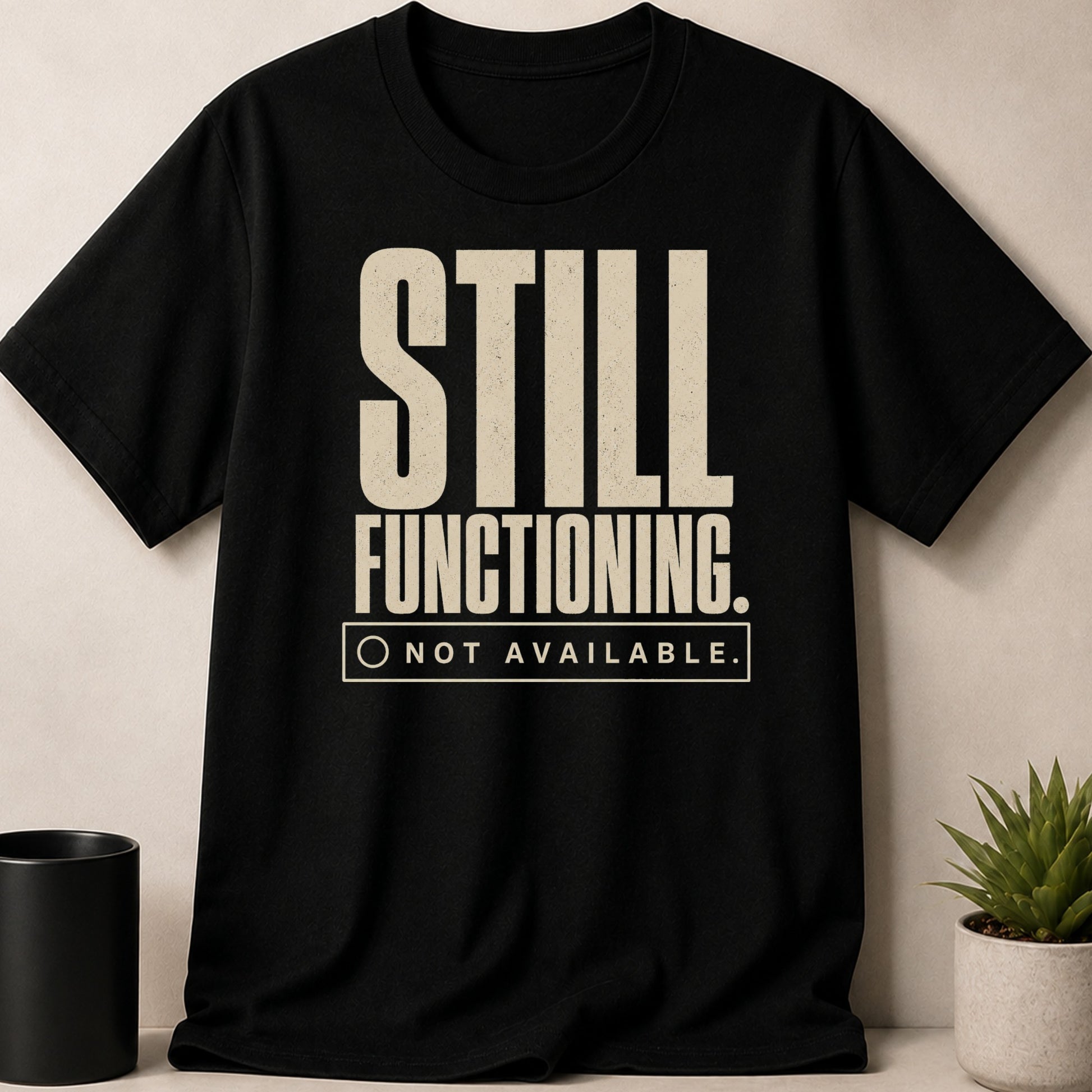 Black t-shirt with "STILL FUNCTIONING. NOT AVAILABLE." text and a circle checkbox.