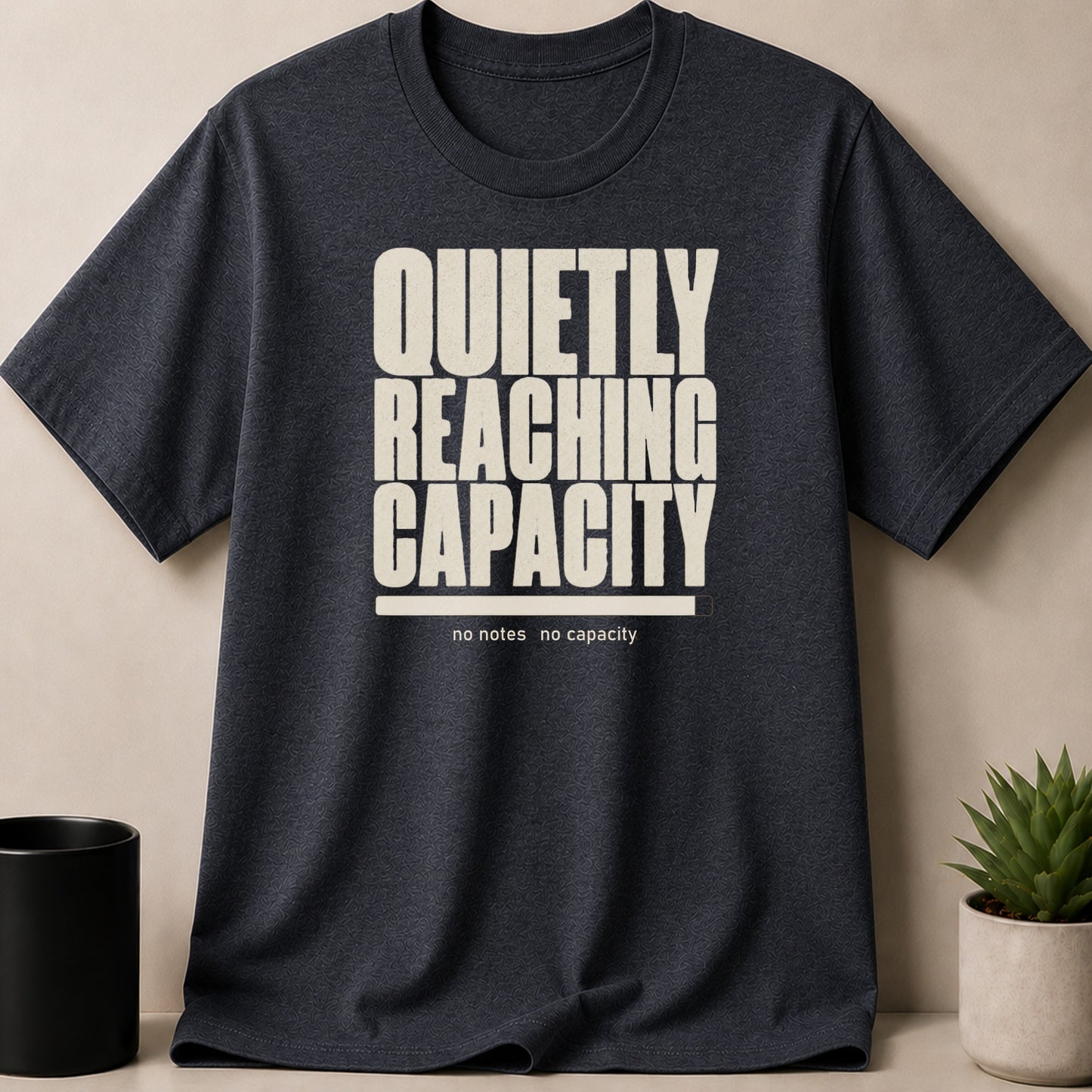 Dark grey t-shirt with "QUIETLY REACHING CAPACITY" and a progress bar.